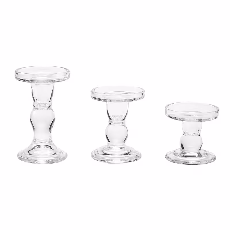 Three clear glass pillar pedestal candle holders shown empty in graduated heights on a white background, revealing their round flat tops and bulb stems