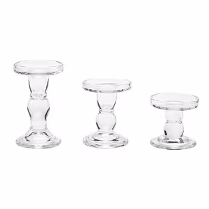 Three clear glass pillar pedestal candle holders shown empty in graduated heights on a white background, revealing their round flat tops and bulb stems
