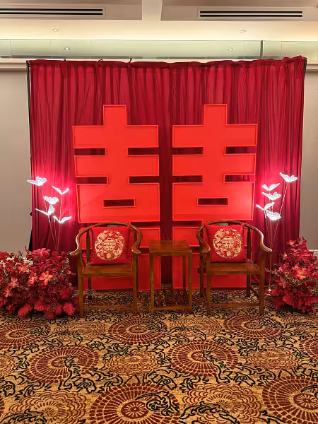Chinese wedding 囍 Double Happiness backdrop with red pleated curtain, rustic wooden chairs, butterfly LED lights, and red floor flowers