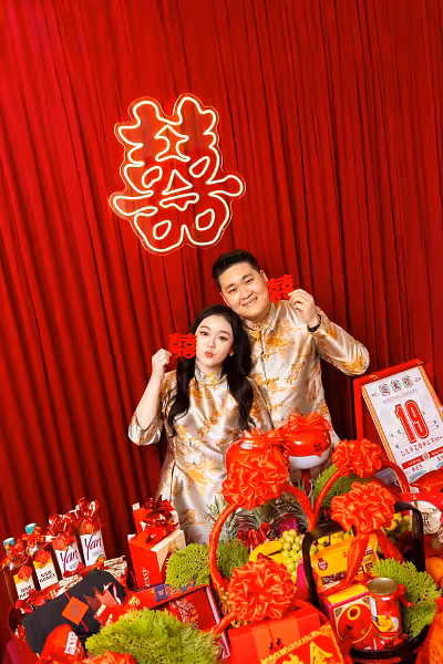囍 Double Happiness LED neon signage on a rich red pleated fabric backdrop with traditional betrothal gift displays