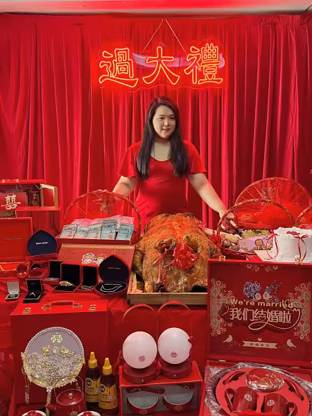 過大禮 GuoDaLi neon light in gold against a rich red velvet curtain backdrop, above a table of traditional betrothal gifts