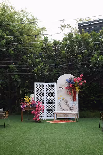White four-leaf clover pattern room divider and arched floral backdrop with pink, yellow, and blue blooms on a garden lawn
