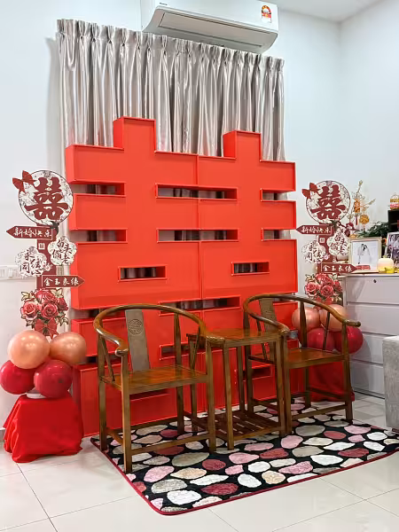 Bold red 2-metre 囍 Double Happiness backdrop flanked by floral signage and balloon clusters, with rustic walnut horseshoe chairs on a patterned rug
