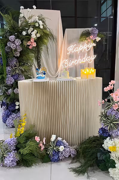 Origami dessert table with Happy Birthday neon sign, Sweet Forest flower arches in purple, pink, and white, and LED acrylic candles