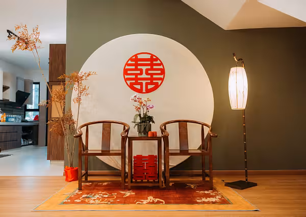 Beige round arch backdrop with red double happiness symbol, walnut chairs and table set on a vibrant red oriental carpet