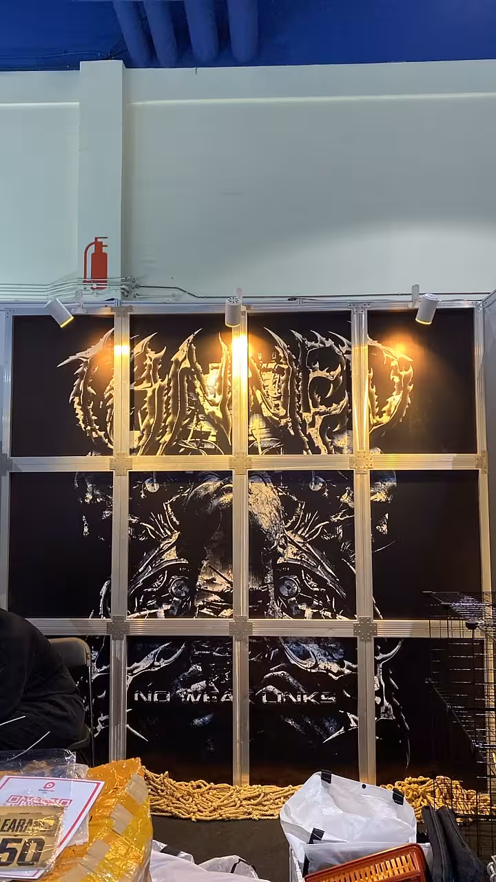 Dark graphic exhibition booth backdrop panel illuminated by warm white LED clip spotlights mounted on aluminium frame