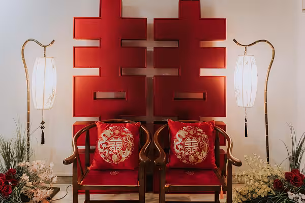 2-metre 囍 Double Happiness red backdrop flanked by bamboo zen floor lamps and walnut chairs with embroidered dragon phoenix cushions