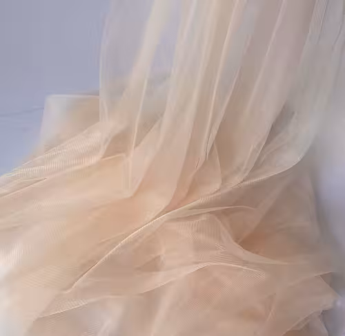 Close-up of champagne nylon netted decorative cloth showing soft sheer layers with delicate rippled folds and a semi-transparent finish