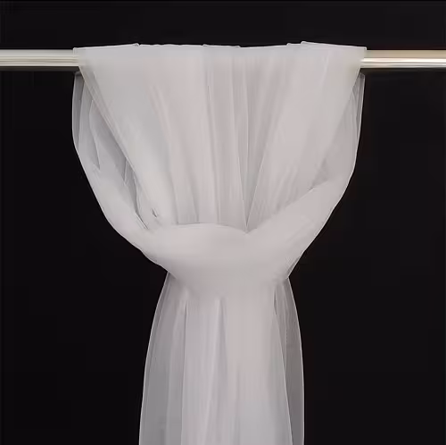 White sheer netted nylon fabric looped over a silver rod and knotted into a full swag against a black background