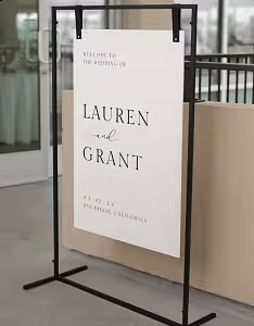 Black Rectangle Decorative Screen Arches Frame displayed at a slight angle, holding a minimalist white wedding welcome board in an indoor venue