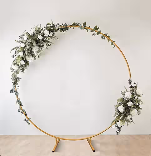 Gold Round Stand styled with white roses, lush greenery and eucalyptus garland cascading across the upper-left arc and lower-right side