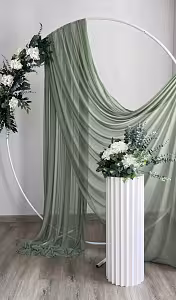 White Round Stand draped with sage green chiffon fabric, styled indoors beside a white fluted pedestal topped with white hydrangeas and eucalyptus