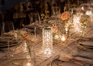 Crystal Rose Lamp glowing warm white as a wedding tablescape centrepiece, surrounded by blush roses, baby's breath, and wine glasses