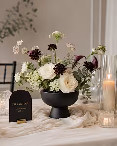 Matte black Pedestal Bowl Vase styled as a wedding centrepiece with cream roses, burgundy blooms, and a Thank You card on a draped table