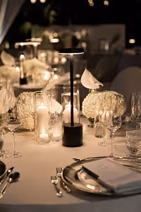 Matte black I-shaped Portable LED Table Lamp glowing softly among white florals, candles, and crystal glassware at an elegant wedding reception
