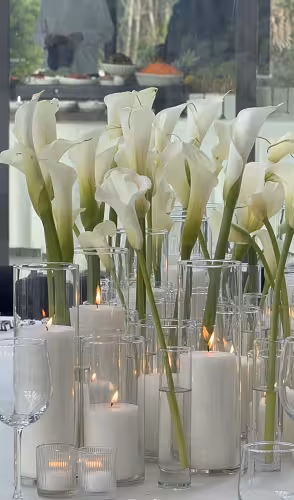 Multiple Minimalist Cylinder Clear Glass Vases grouped as an elegant wedding centrepiece with white calla lilies and lit pillar candles