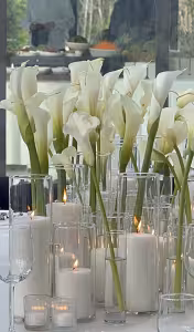 Multiple Minimalist Cylinder Clear Glass Vases grouped as an elegant wedding centrepiece with white calla lilies and lit pillar candles