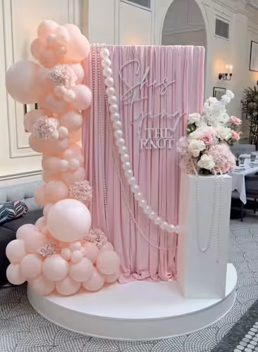 Stretchable Pink Drape Backdrop Fabric styled at a bridal event with pink balloon garland, pearl strand, and floral arrangement