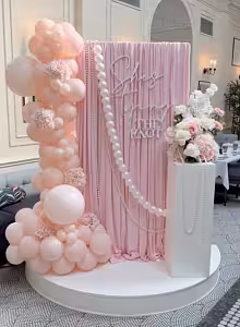 Stretchable Pink Drape Backdrop Fabric styled at a bridal event with pink balloon garland, pearl strand, and floral arrangement