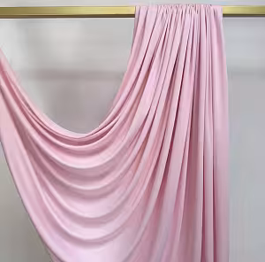 Stretchable Pink Drape Backdrop Fabric gathered on a gold bar, cascading in a sweeping diagonal swag across a white wall