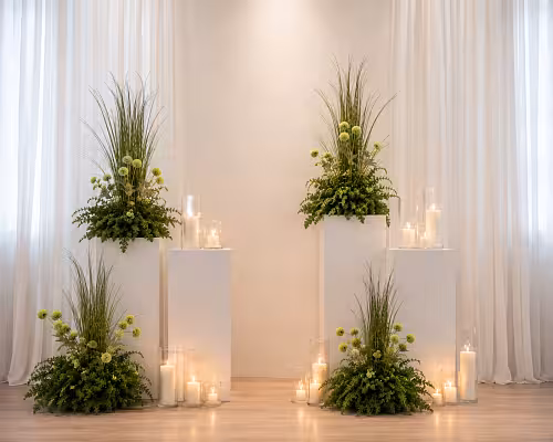 Grassy Green Artificial Floor Flowers styled as altar decor flanking white pedestals, paired with candles and fern foliage in a bright draped venue