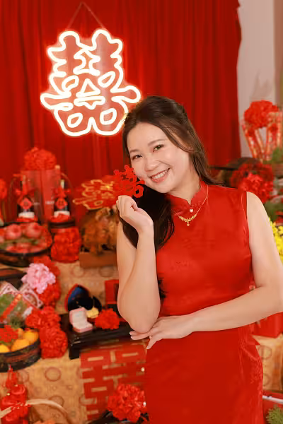 Glowing 囍 Double Happiness LED neon sign against a red draped backdrop with traditional Chinese wedding decor and red floral arrangements
