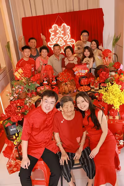 囍 Double Happiness LED neon sign glowing above a red draped backdrop and an elaborate traditional betrothal gift table adorned with red floral arrangements, gold accents, and festive offerings