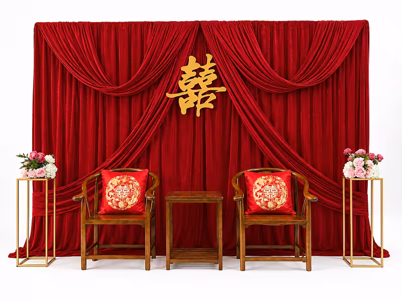 Grand Drape Chinese Tea Ceremony Backdrop with rich red velvet draping, gold double-happiness symbol, wooden chairs with red embroidered cushions, and pink floral stands