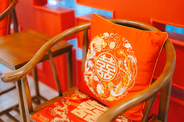 Red embroidered dragon and phoenix cushion with Double Happiness motif on a wooden Chinese chair, with a matching kneeling cushion beneath