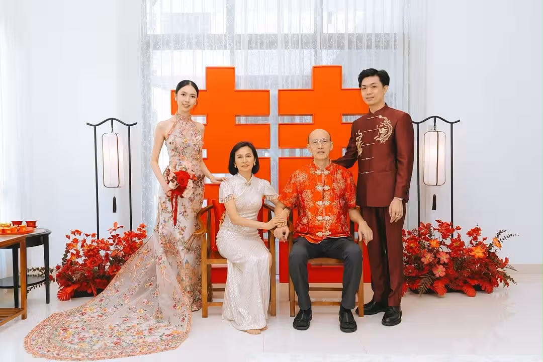 Bold red 囍 Double Happiness backdrop flanked by retro lantern floor lamps, rustic walnut chairs, and lush red artificial floor flowers