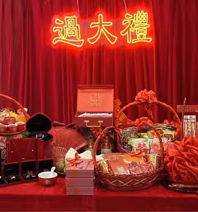 Close-up of GuoDaLi betrothal bundle display with red gift baskets, jewellery boxes, double-happiness trinket box, and traditional items arranged on a draped table
