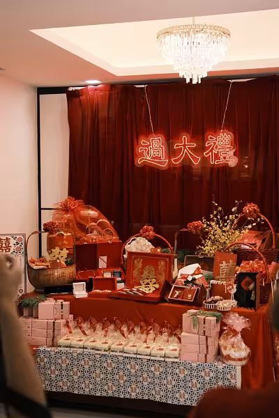 过大礼 neon light signage on a deep wine red velvet backdrop curtain over a draped betrothal gift display table