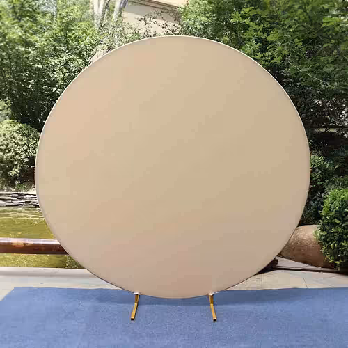 Cream Round Elastic Cloth Arch Stand displayed outdoors, full-circle taut fabric backdrop on short gold feet against lush greenery