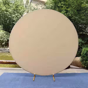 Cream Round Elastic Cloth Arch Stand displayed outdoors, full-circle taut fabric backdrop on short gold feet against lush greenery